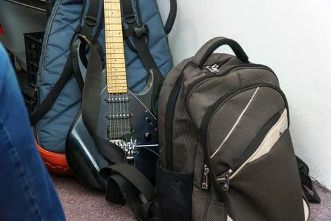 A black guitar, a case and a backpack are the musicians touring kit in the room 写真素材