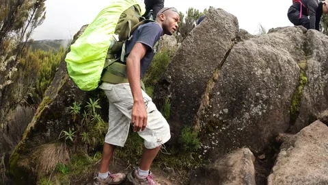 A black guy with a big backpack climbs up the rocks Stock-Footage 169338176