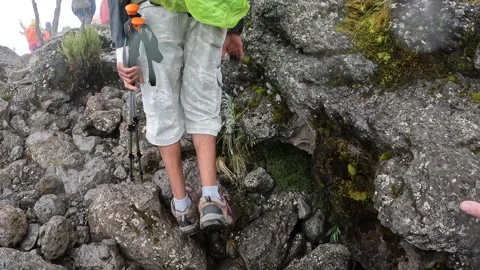 Black guy with a big backpack climbs dangerous wet rocks uphill Video stock 169338461