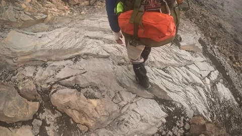 A black guy with a big backpack walks along a mountain path Stock-Footage 169224830