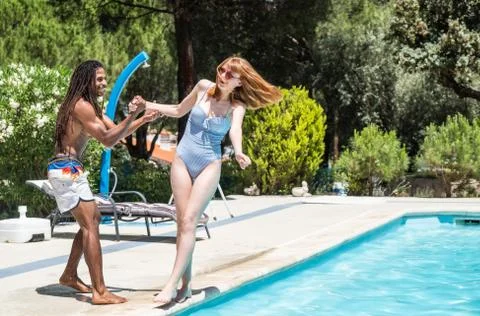 Black guy with dreadlocks playing in a pool with caucasian girl. Stock Photos