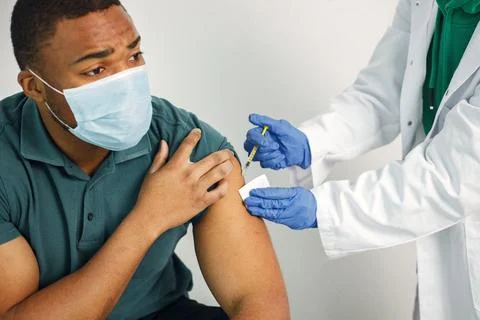 Black guy in face mask holding a poster with words vaccination saves lives Stock Photos
