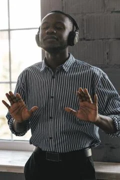 Black guy on a gray background listens to music enjoys great sound and dances Fotos Stock