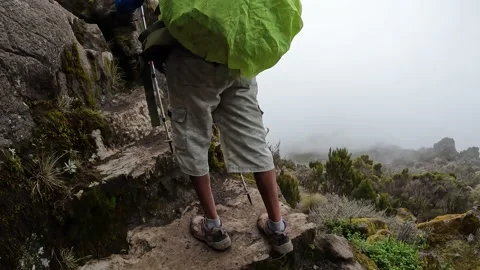 A black guy with a green backpack climbs up the large stone steps Video stock 169337695