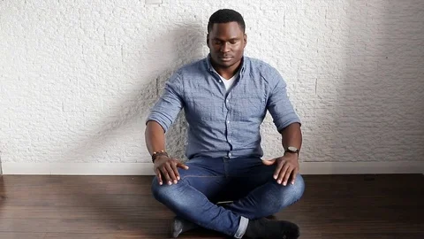Black guy meditates sitting on the floor Stock Footage 77247990