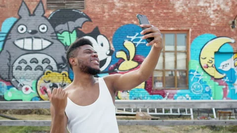 Black Guy Poses In Front Of The Camera Of His Phone. In The Background Are 스톡 동영상 142160568