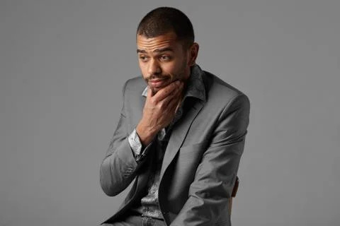 Black guy thinking in gray blazer isolated on gray background Stock Photos