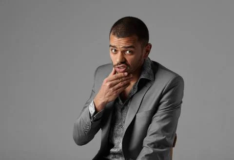 Black guy thinking in gray blazer isolated on gray background Stock Photos