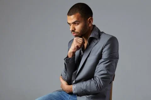 Black guy thinking in gray blazer isolated on gray background Stock Photos