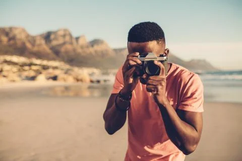 Black guy using digital camera on beach Stock Photos