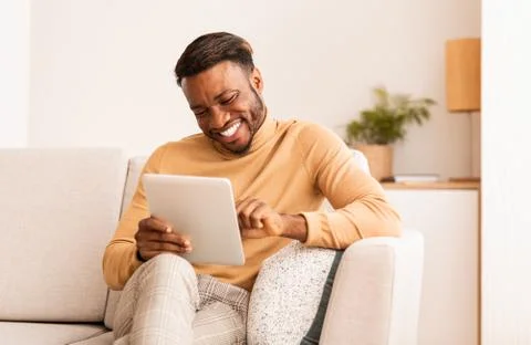 Black Guy Using Tablet Smiling Sitting On Sofa At Home Photos