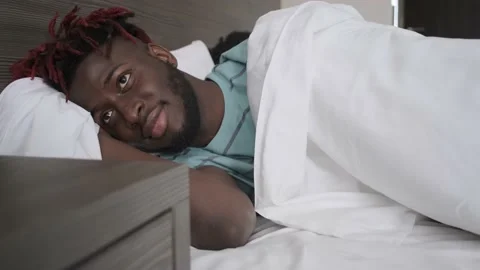 The black guy wakes up. Opens his eyes. He smiles. Stock Footage 151001199