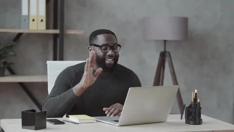 Black guy waves his hand into a laptop and communicates via video link in casual Stock Footage 134448619