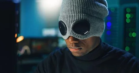 Black hacker in mask using computer Foto stock