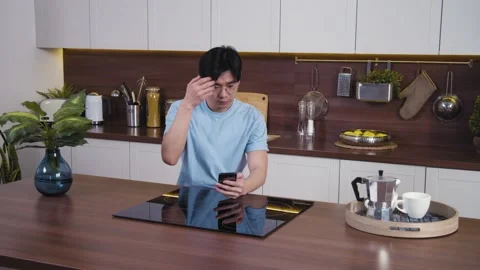Black haired asian man touching hair and looks at selfie camera of smartphone Stock Footage 153477850