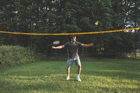 Black-haired badminton player practices his strokes on the grass court. Indiv Stock Photos