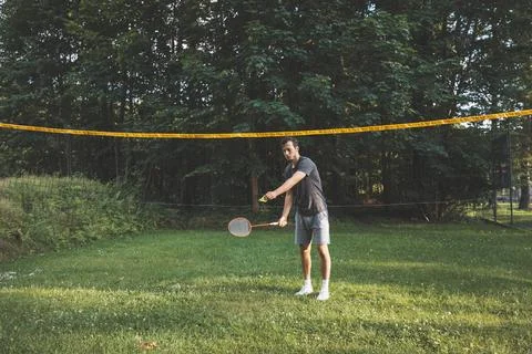 Black-haired badminton player practices his strokes on the grass court. Indiv Stock Photos
