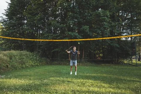 Black-haired badminton player practices his strokes on the grass court. Indiv Stock Photos