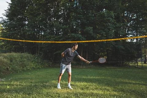 Black-haired badminton player practices his strokes on the grass court. Indiv Stock Photos