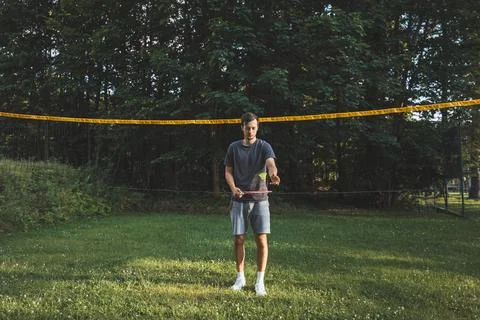 Black-haired badminton player practices his strokes on the grass court. Indiv Stock Photos