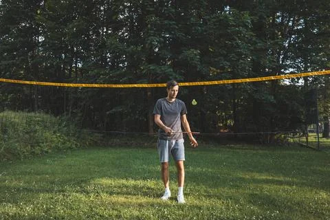 Black-haired badminton player practices his strokes on the grass court. Indiv Stock Photos