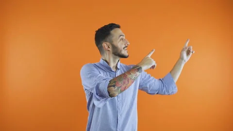 Black haired man pointing with fingers up at invisible product, isolated on Stock Footage 138436649