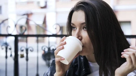 Black haired woman drinking a coffee to go in a cafe outdoors Stock Footage