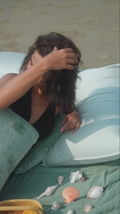 Black-Haired Woman Posing on Beach Among Pillows and Shells Video stock 320152565