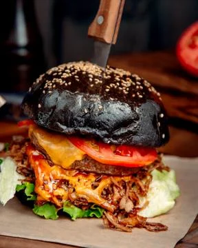 Black hamburger with knife on the table Stock Photos