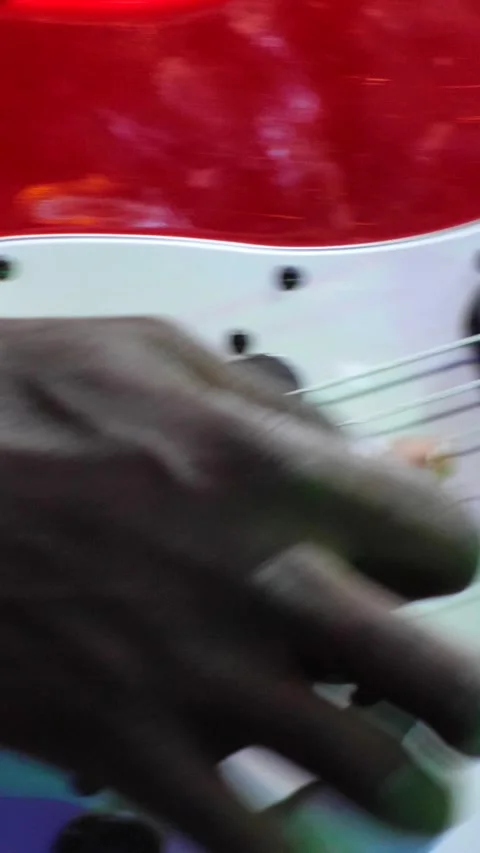 Black hand playing with plectrum on red and white electric guitar, light show Stock Footage 230686230