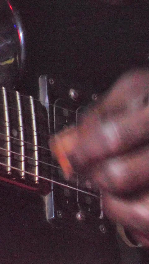 Black hand with ring playing with plectrum on black electric guitar up side down Stock Footage 230686148