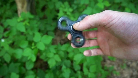 Black hand spinner, or fidgeting spinner, rotating on child's hand.grass Stock Footage 77151628