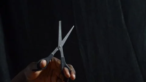 Black hands holding a pair of scissors snapping Stock Footage 276594451