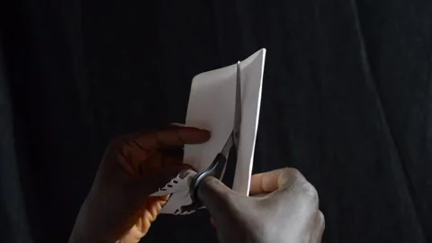 Black hands with a pair of scissors cutting paper Stock Footage 276593878