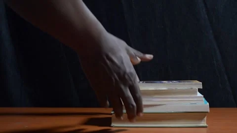 Black hands picking up a stack of books Stock Footage 276593764