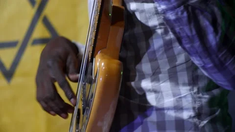 Black hands playing on black and wood electric bass guitar with light show 스톡 동영상 208939996