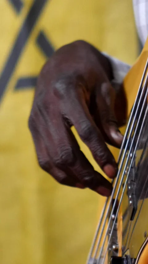 Black hands playing on black and wood electric bass guitar with light show Stock-Footage 230686538