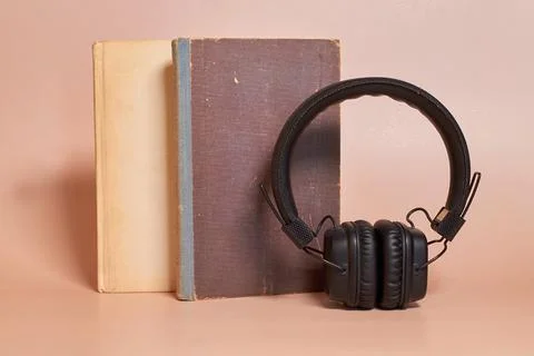 Black headphones stand next to a stack of old books Stock Photos