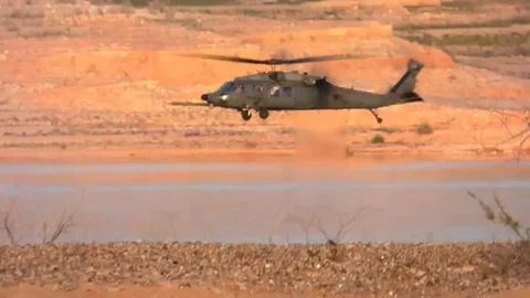 Black Helicopter Hovering Over Desert Near Lake Video stock 73344653