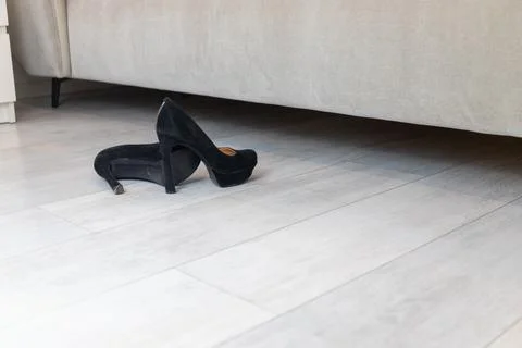 Black high heels in front of a bed Stock Photos