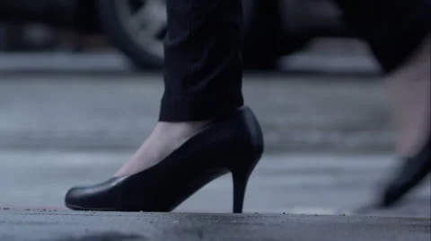 Black high heels walk through frame on a busy street, still wet from rain. Stock Footage 64862852