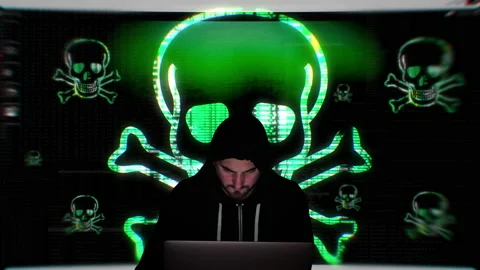 Black hooded hacker programs computer virus in front of huge laughing Stock Footage 147673606