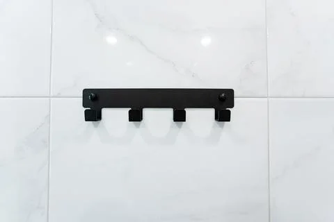 A black hook hangs on a white tiled wall in a monochrome setting 写真素材