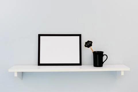 A black horizontal frame, next to a black cup Stock-Fotos