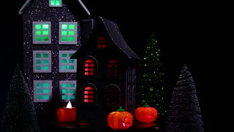 A black house surrounded by glowing pumpkins rotates against of a large house Stock Footage 319392400