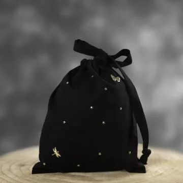 Black hygiene draw-string bag dotted with stars, displayed on a wooden disc Foto stock