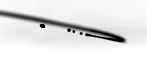 Black ink drops splatters spilling on white background Stock Footage 125476911