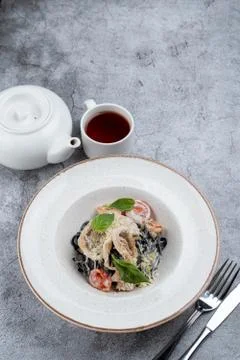 Black ink pasta with prawns, squid and creamy parmesan sauce Stock Photos