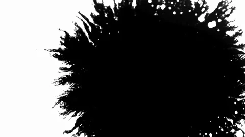 Black ink splatter expands slowly on white paper background Stock Footage 329667609