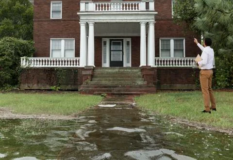 Black insurance adjuster examining flooding damage to house Stock Photos